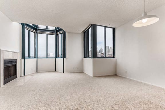 an empty room with a fireplace and three windows