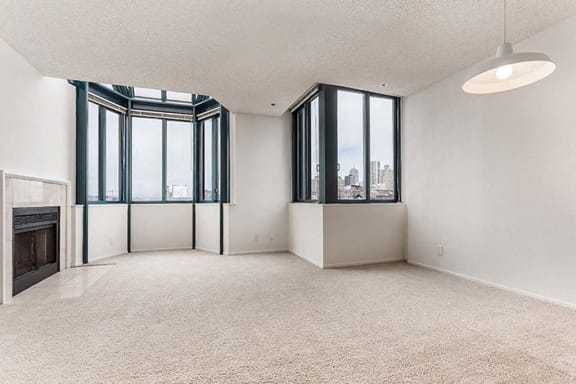 an empty room with a fireplace and three windows