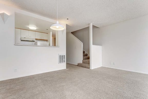 an empty living room with a staircase in the background