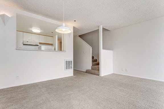 an empty living room with a staircase in the background