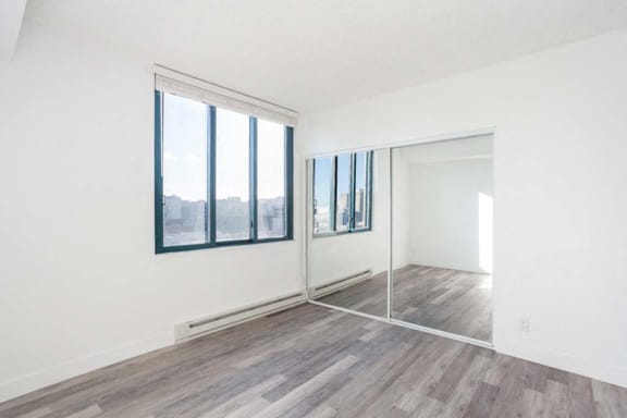 an empty room with a large window and a mirrored door