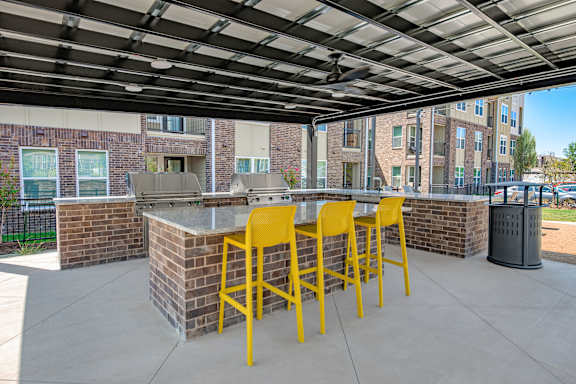 A yellow bar with four stools is under a roof.