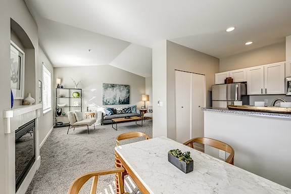A modern kitchen with a marble table and wooden chairs.