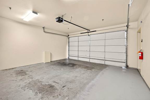 A garage with a white door and a fire extinguisher on the wall.