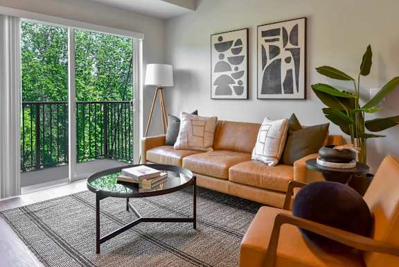 A living room with a tan couch, a glass table, and a lamp.
