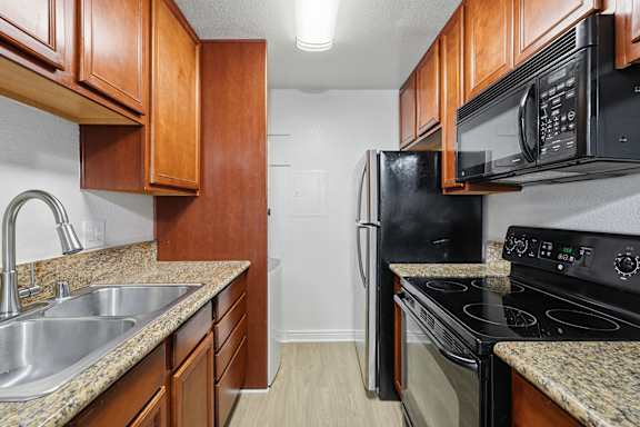 A kitchen with black appliances and wooden cabinets.