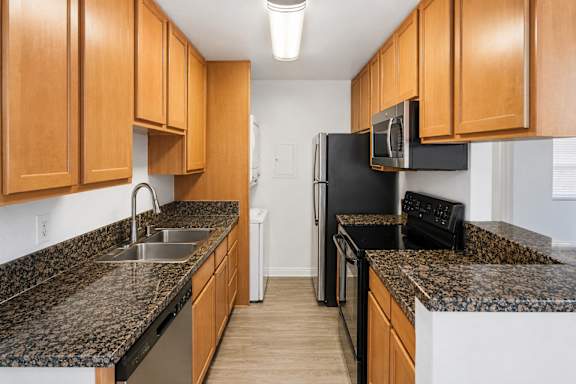 A kitchen with black appliances and wooden cabinets.