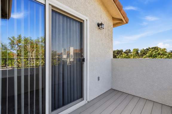 A balcony with a glass door and a white wall.