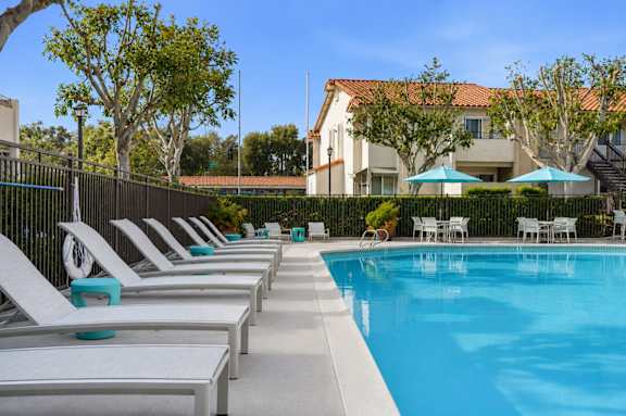 A resort style swimming pool with lounge chairs and umbrellas.