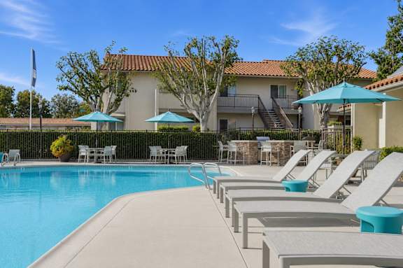 A resort style swimming pool with lounge chairs and umbrellas.