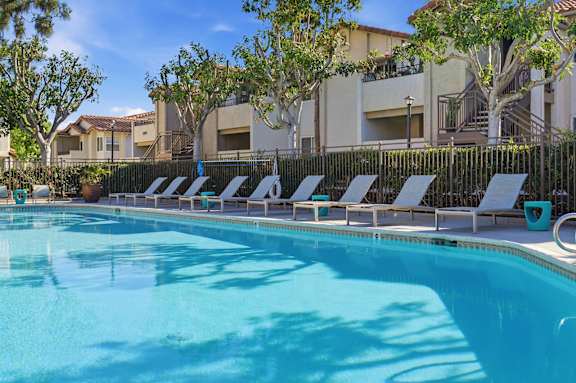 A resort style swimming pool with lounge chairs and umbrellas.