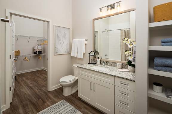A bathroom with a toilet, sink, and mirror.