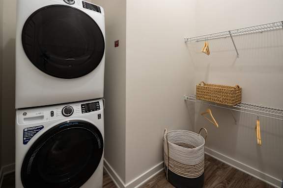 A white washing machine is stacked on top of another in a laundry room.