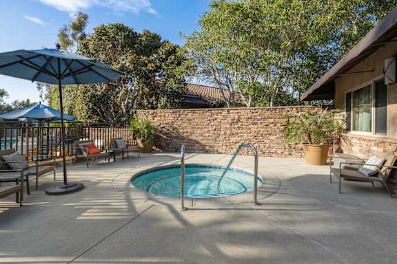 A pool with a blue umbrella and a stone wall.
