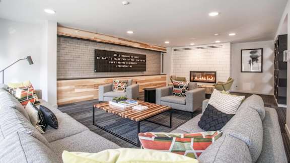 A living room with a grey couch, a coffee table, and a wooden wall.at Axle, Seattle