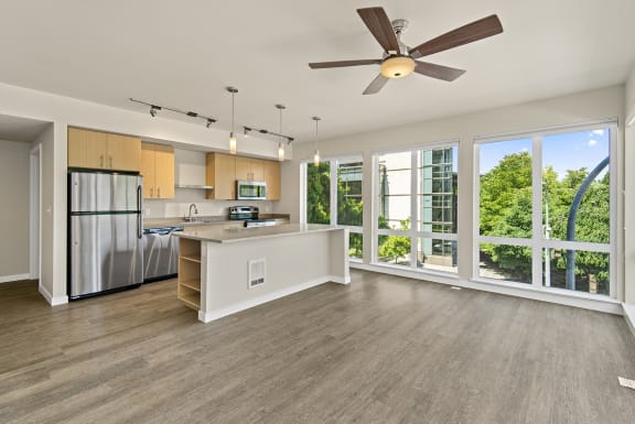 a kitchen and living room with large windows and a ceiling fan at Allez, Redmond, 98052