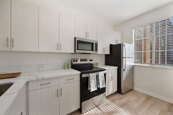 A kitchen with white cabinets and a black stove top.