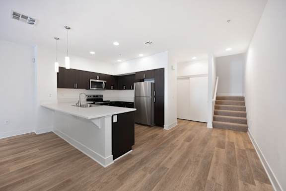 A kitchen with a refrigerator, microwave, and stove top oven.