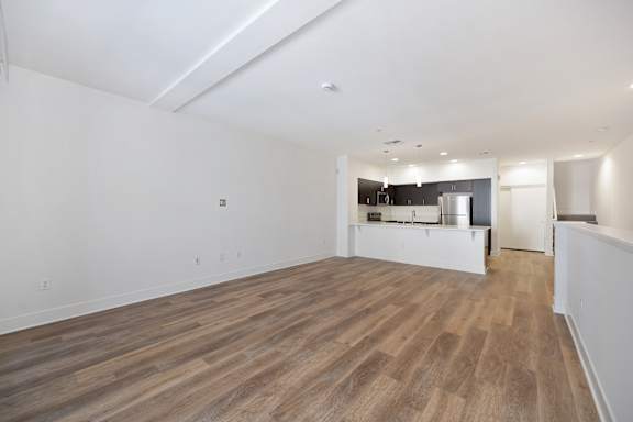 A large empty room with wooden flooring and white walls.