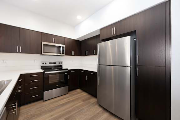 A modern kitchen with dark wood cabinets and stainless steel appliances.