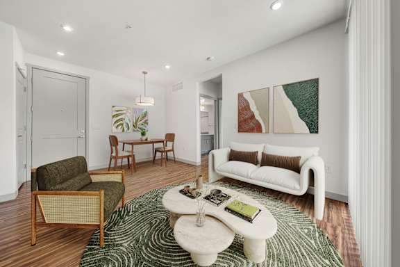 A living room with a white couch, a green rug, and a coffee table with a book on it.