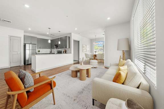 A modern living room with a white sofa and orange armchair.