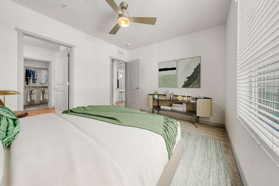 A bedroom with a bed, a dresser, and a ceiling fan.