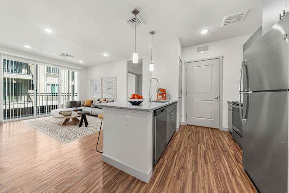A modern kitchen with wooden floors and stainless steel appliances.