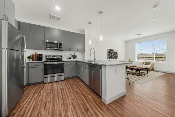 A modern kitchen with stainless steel appliances and wooden flooring.