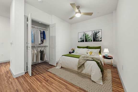A bedroom with a bed, a ceiling fan, and a wardrobe.