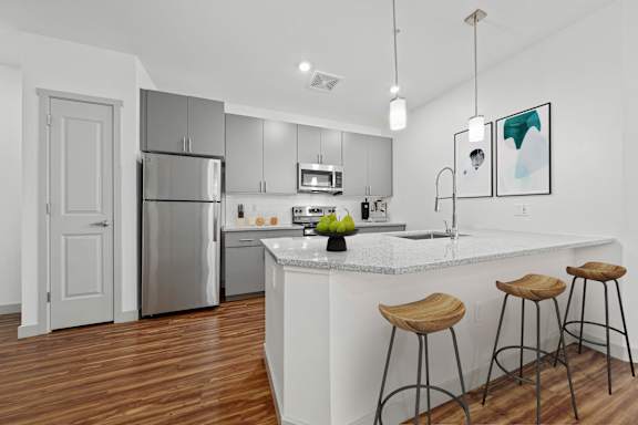 A kitchen with a white island and wooden stools.