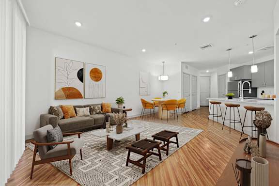 A modern living room with a grey sofa, wooden coffee table, and a kitchen area in the background.