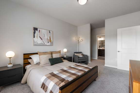 A bedroom with a bed, nightstands, and a chair.