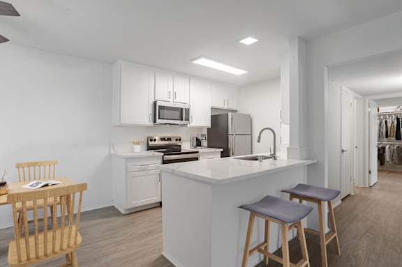 A modern kitchen with a white island and wooden stools.