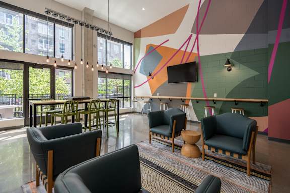 A modern lounge area with black leather chairs and a colorful mural on the wall.