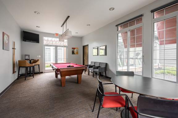 A room with a pool table and chairs.