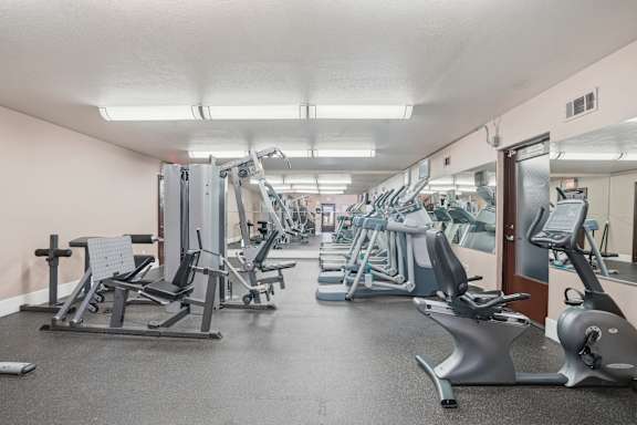 A gym with a variety of equipment including treadmills, stationary bikes, and weight machines.
