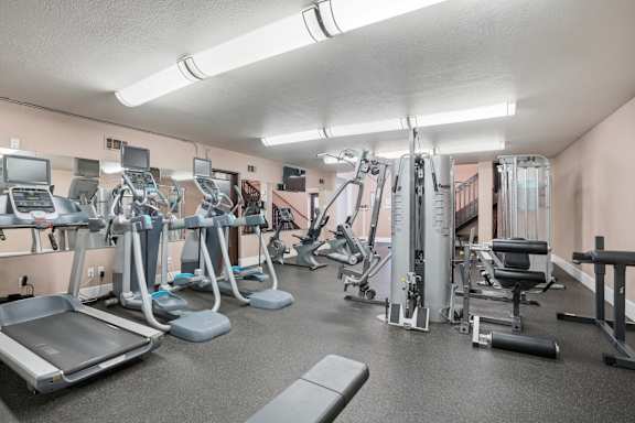A gym with a variety of equipment including treadmills, weights, and exercise machines.
