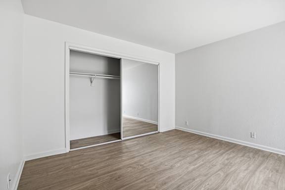 A room with a white wall and a white closet with a mirror.