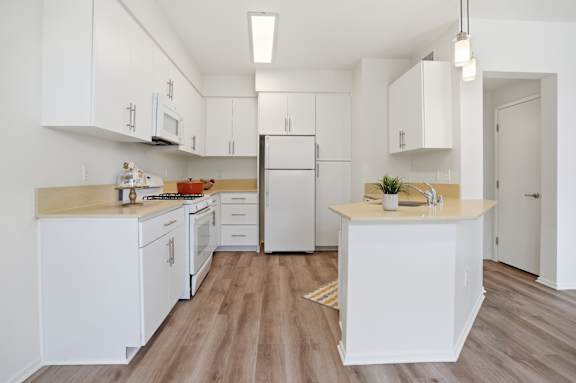 A kitchen with white cabinets and a wooden floor.