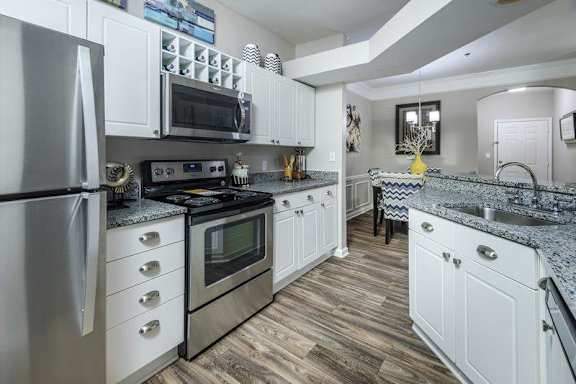 A kitchen with white cabinets and a granite countertop.