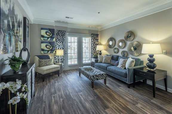 A living room with a grey sofa, a zebra print ottoman, and a wooden floor.