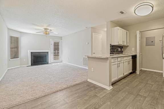 A living room with a fireplace and a kitchen area in the background.