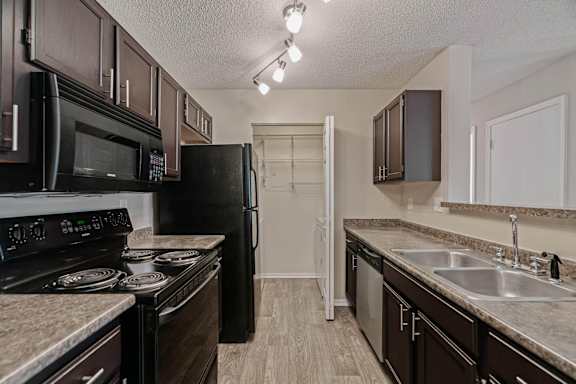 A kitchen with black appliances and brown cabinets.