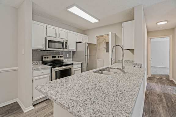 A kitchen with a granite countertop and white cabinets.