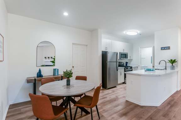 A kitchen with a table and chairs in the foreground and a refrigerator in the background.