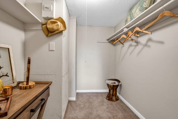 a walk in closet in a bedroom with a large mirror and a wooden stool  at Castilian Apartments, Orlando, 32839