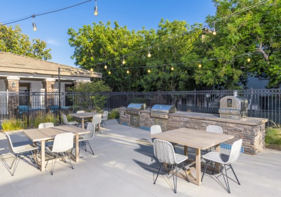 a patio with tables and chairs and a barbecue grill