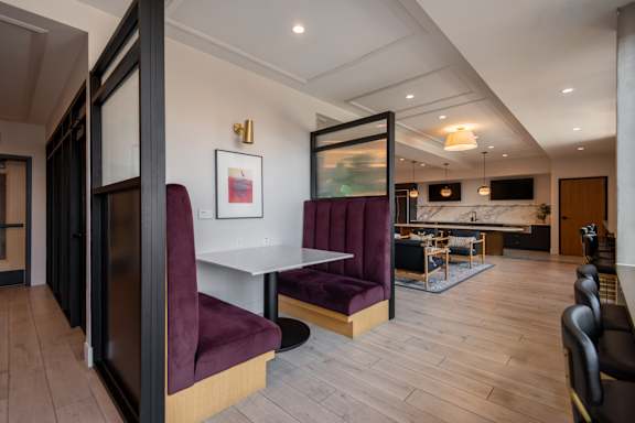 A modern dining room with a white table and purple chairs.