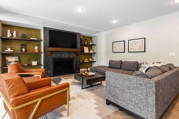 A living room with a fireplace and a grey couch.